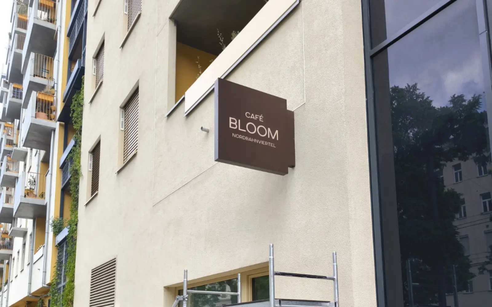 Montage des Café-Bloom-Schilds an der Fassade